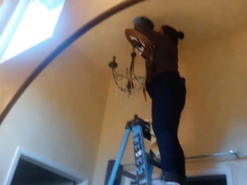 Electrician installing a chandelier in a Felton residence